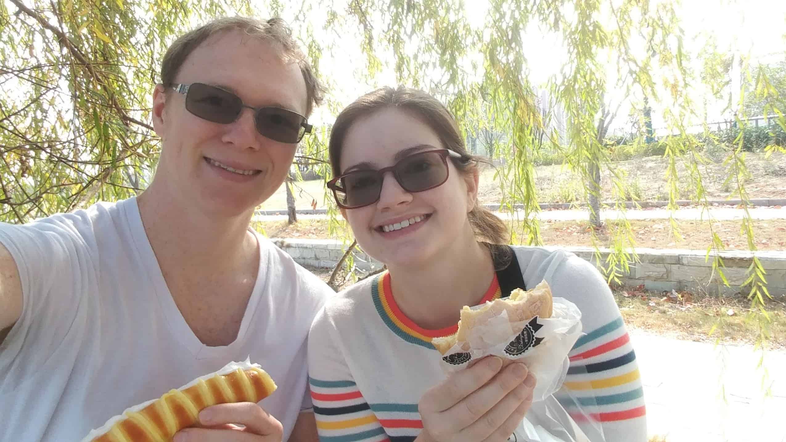 Derek and Kacie eating bakery goodies under a willow tree in Nanjing, China
