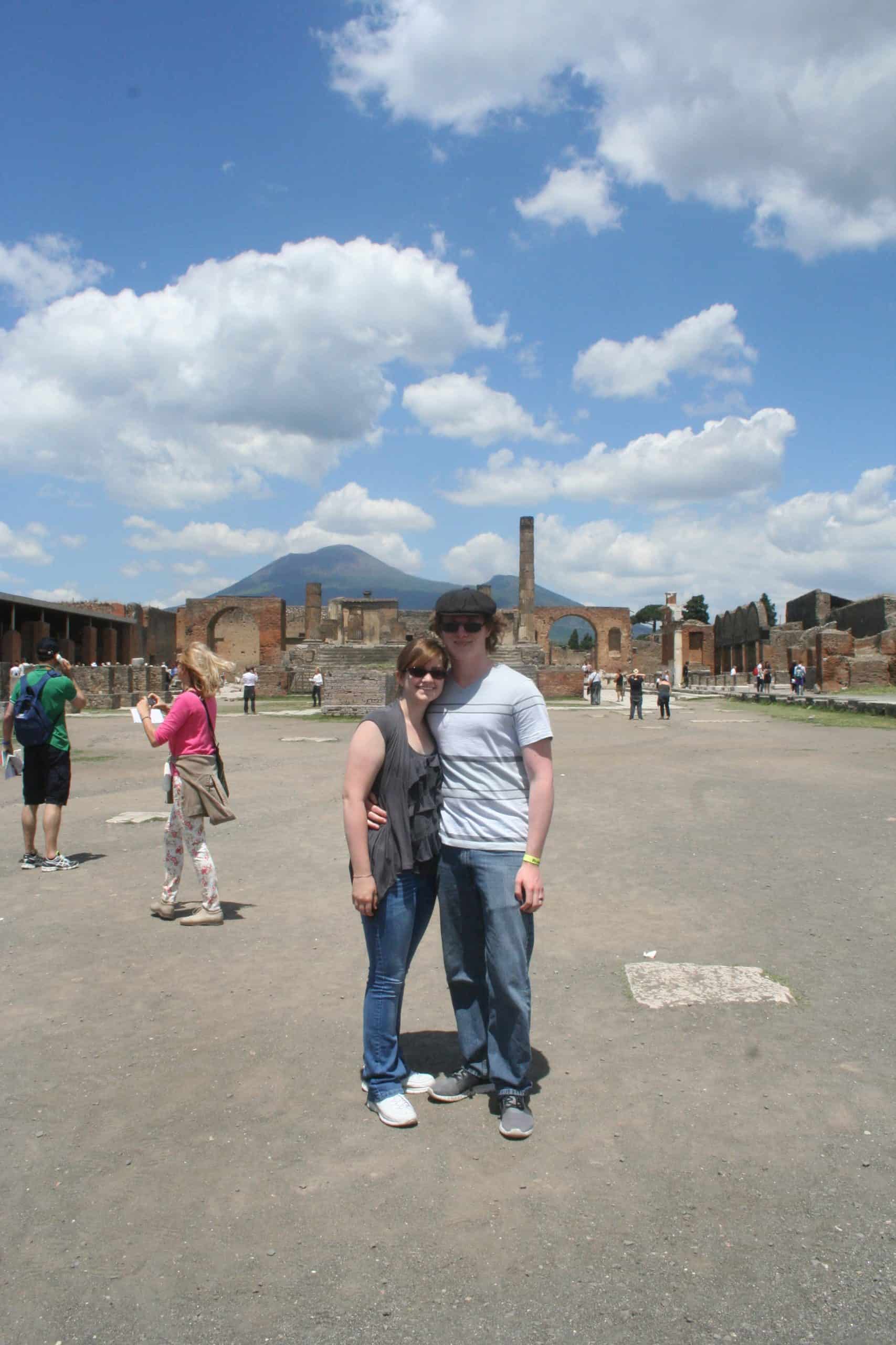 Kacie and Derek standing in Pompeii with a view of Mt. Vesuvius in the background.