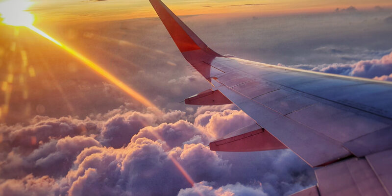 Airplane in flight with sun above the clouds